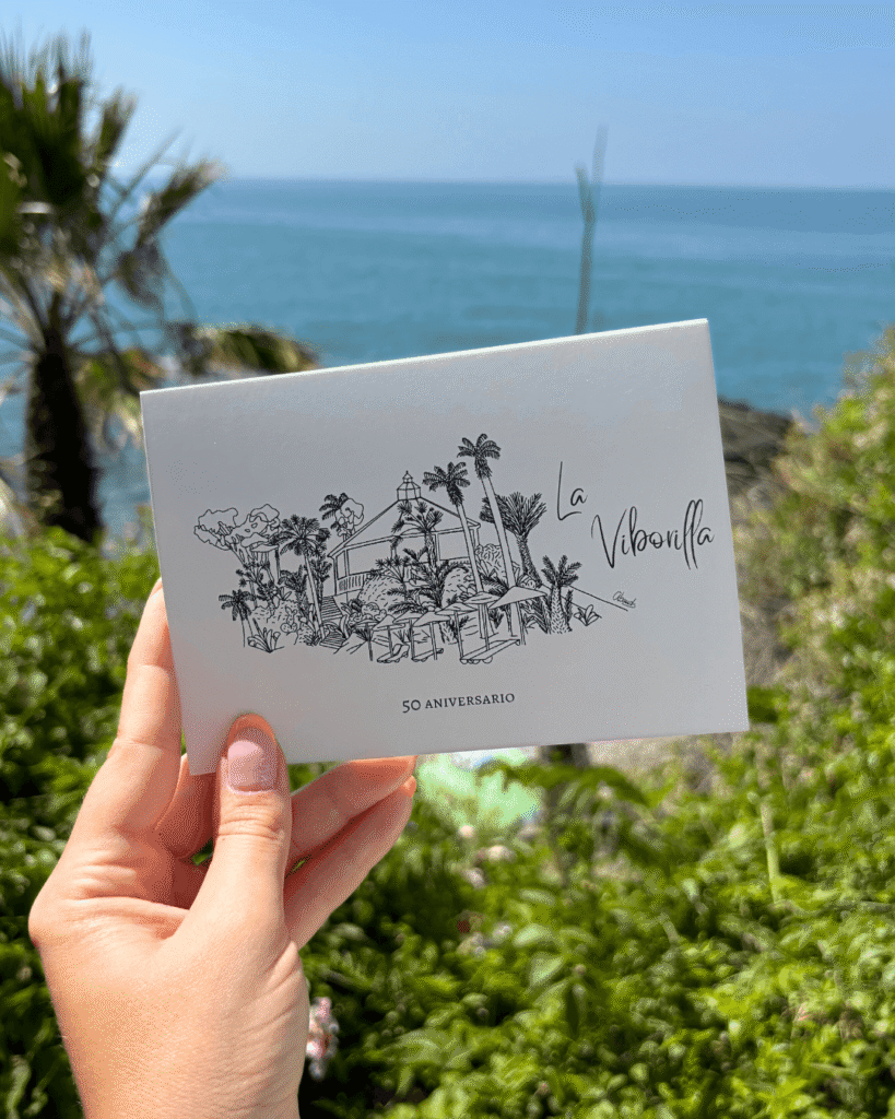 Recordatorio aniversario con diseño minimalista y motivos botánicos en blanco y negro frente al mar.